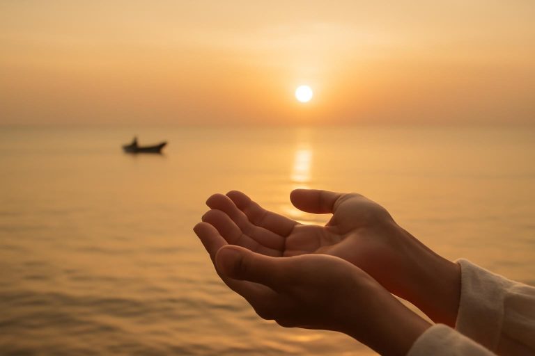 Mãos abertas recebendo luz dourada sobre o oceano ao amanhecer, simbolizando abundância espiritual e fé.