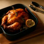Frango inteiro assado no air fryer oven, com pele dourada e crocante, decorado com alecrim e limão.