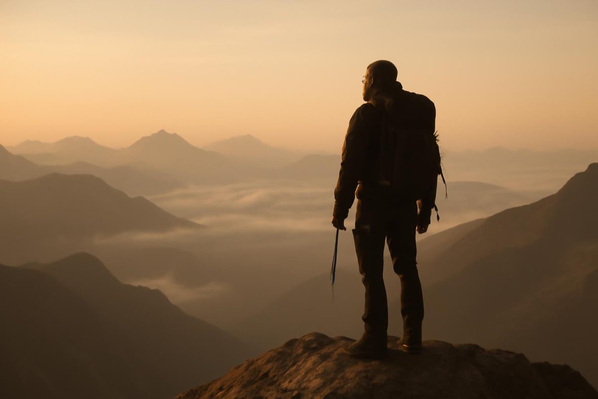 Alpinista no topo de uma montanha ao amanhecer, simbolizando a pressão e o peso do legado após a vitória.