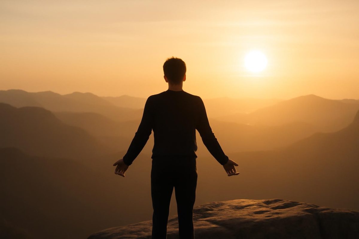 o que é entusiasmo? significado, origem e por que ele move ações 1 Pessoa em pé diante de paisagem ao amanhecer, simbolizando entusiasmo como energia interna que move ações.