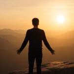 Pessoa em pé diante de paisagem ao amanhecer, simbolizando entusiasmo como energia interna que move ações.